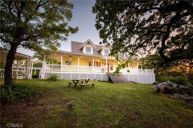 rear view of house with covered porch and a yard