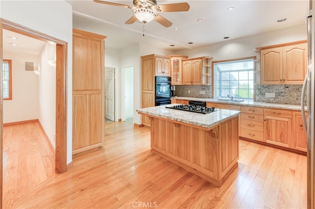 kitchen with sink, backsplash, black appliances, and a kitchen island