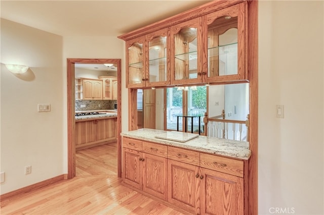 kitchen featuring light stone counters, backsplash, and light hardwood / wood-style flooring