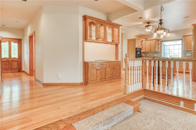 kitchen with light hardwood / wood-style floors, black oven, ceiling fan, tasteful backsplash, and pendant lighting