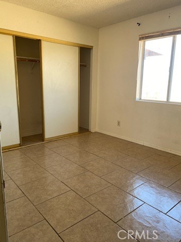 unfurnished bedroom featuring a closet, tile patterned flooring, and a textured ceiling