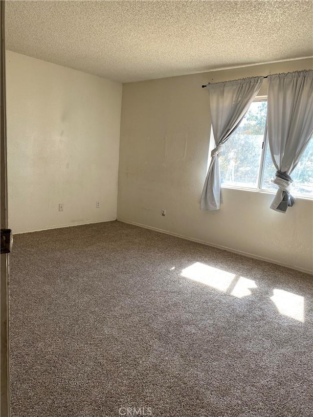 carpeted empty room featuring a textured ceiling and baseboards