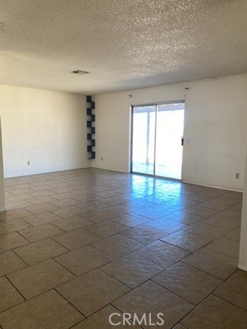 tiled empty room with a textured ceiling