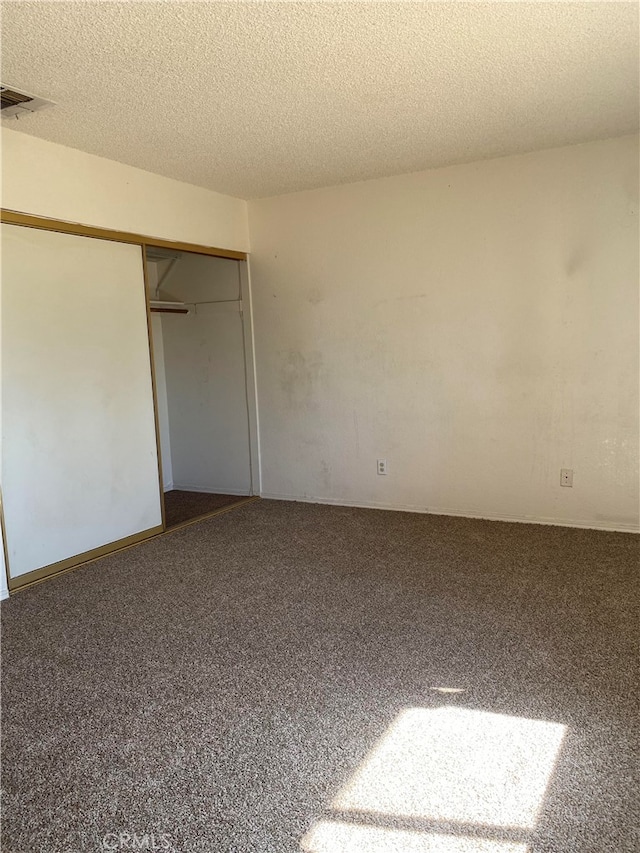 unfurnished bedroom with a textured ceiling, carpet floors, and a closet