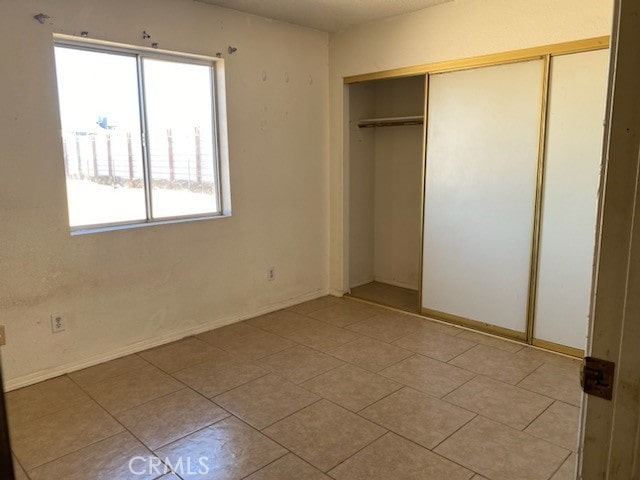 unfurnished bedroom featuring light tile patterned flooring and a closet