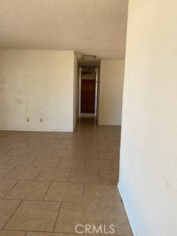 empty room with a textured ceiling and tile patterned flooring