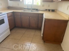 kitchen featuring sink, white range, and light tile patterned flooring