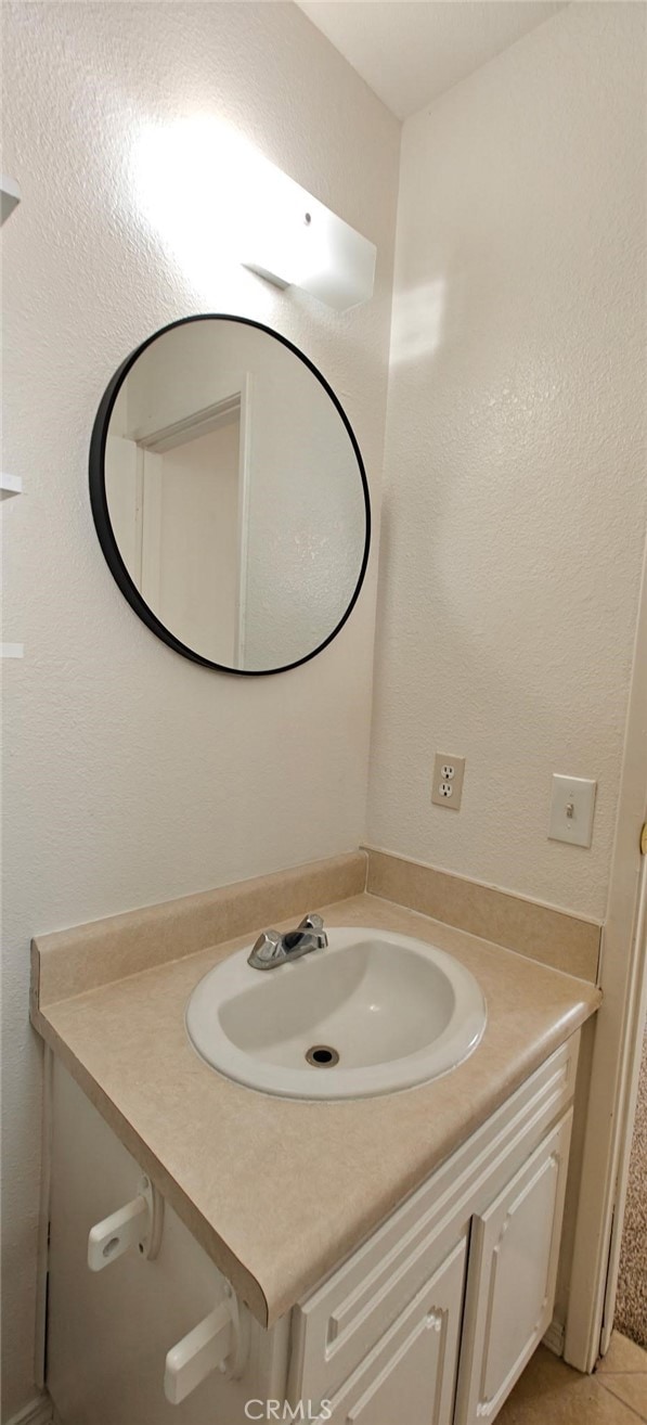 bathroom featuring tile patterned floors, vanity, and a textured wall