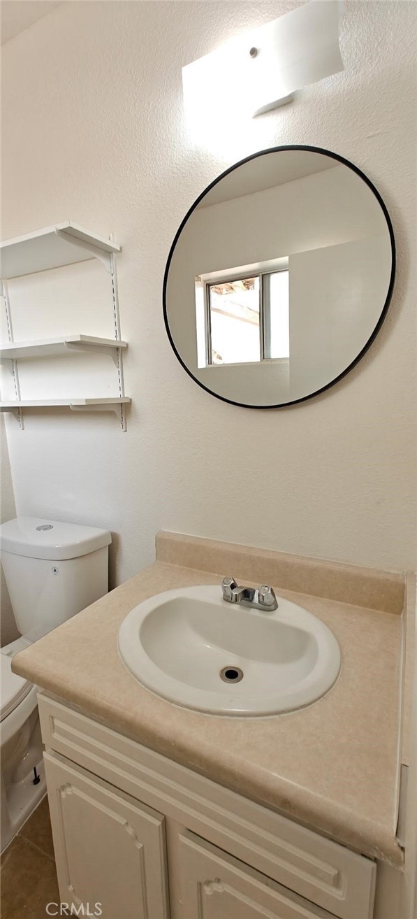 half bath featuring vanity and toilet