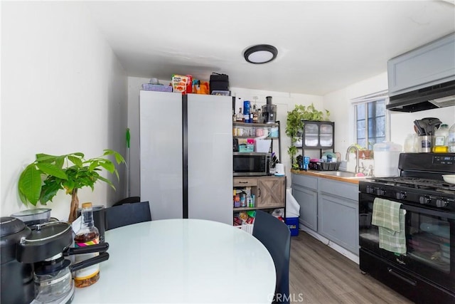 kitchen featuring sink, gray cabinets, fridge, gas stove, and light wood-type flooring