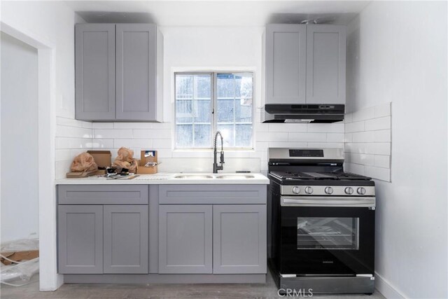 kitchen featuring gray cabinetry, sink, gas range, and tasteful backsplash