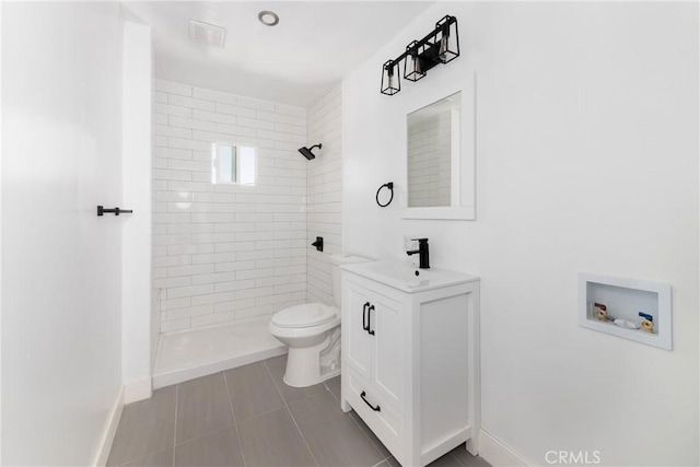 bathroom with vanity, tile patterned flooring, toilet, and tiled shower