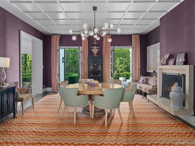 carpeted dining space with coffered ceiling, a healthy amount of sunlight, a notable chandelier, and a premium fireplace