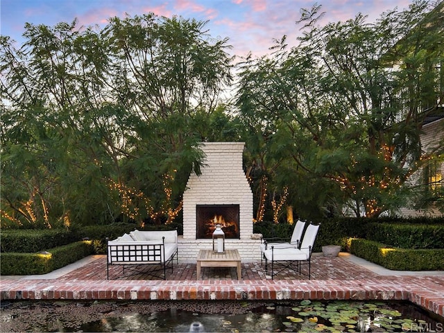 patio terrace at dusk with an outdoor living space with a fireplace