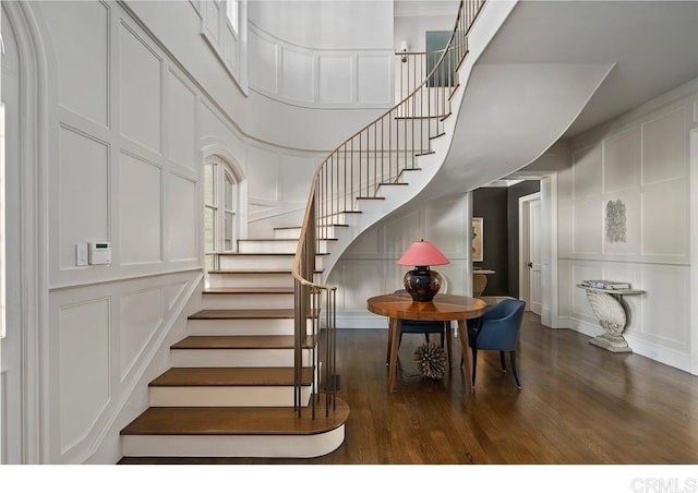 staircase featuring wood-type flooring and a towering ceiling