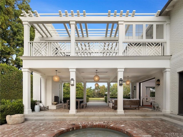 back of property featuring an outdoor hangout area, brick siding, a patio area, and a hot tub