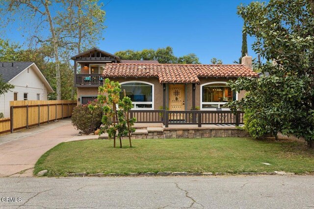 view of front of house with a porch, a balcony, and a front yard