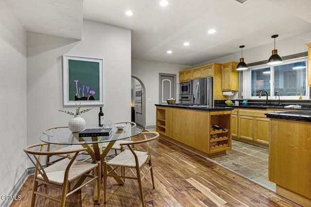 kitchen featuring sink, hanging light fixtures, hardwood / wood-style floors, stainless steel appliances, and light brown cabinets