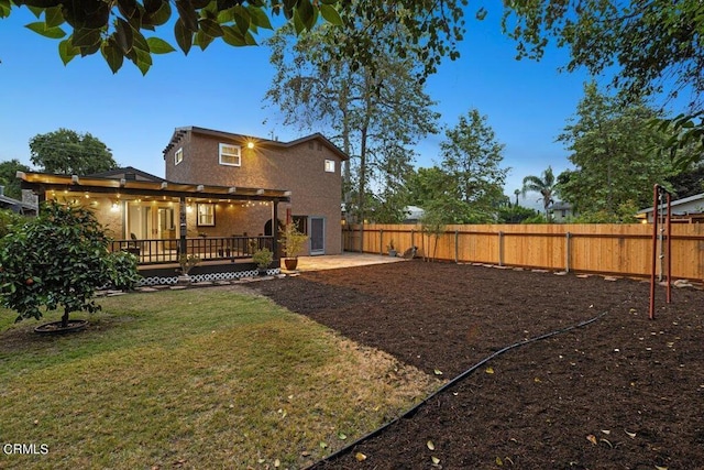 back of house featuring a wooden deck, a lawn, and a patio