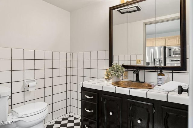 bathroom with tile walls, vanity, and toilet