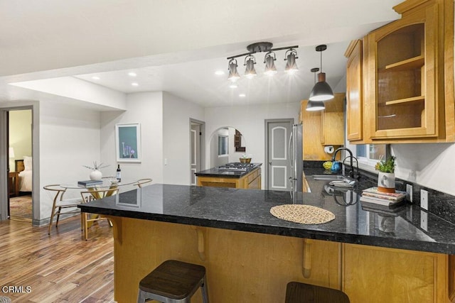 kitchen with pendant lighting, sink, stainless steel refrigerator, a kitchen bar, and kitchen peninsula