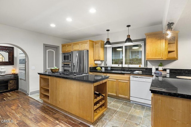 kitchen featuring stainless steel appliances, a center island, sink, and dark stone counters