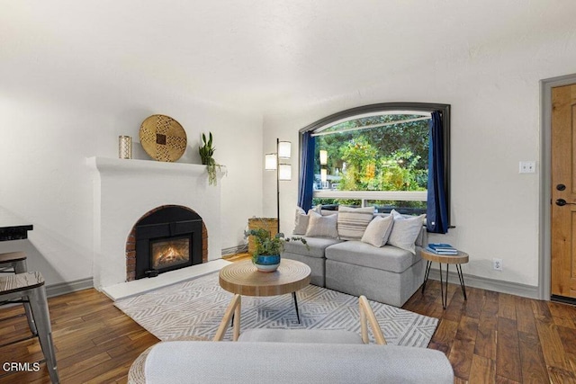 living room featuring a brick fireplace and dark hardwood / wood-style floors