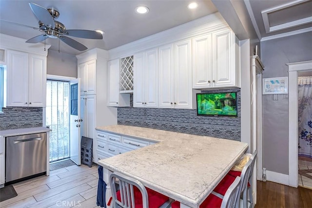 kitchen featuring white cabinetry, light hardwood / wood-style floors, ceiling fan, a kitchen breakfast bar, and stainless steel dishwasher