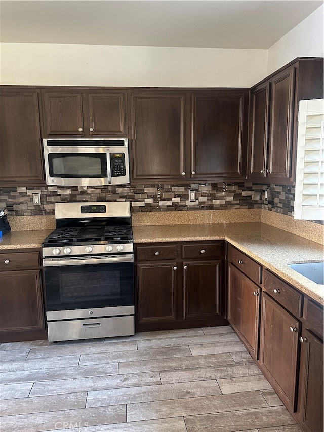 kitchen featuring appliances with stainless steel finishes, decorative backsplash, light wood-type flooring, and dark brown cabinetry