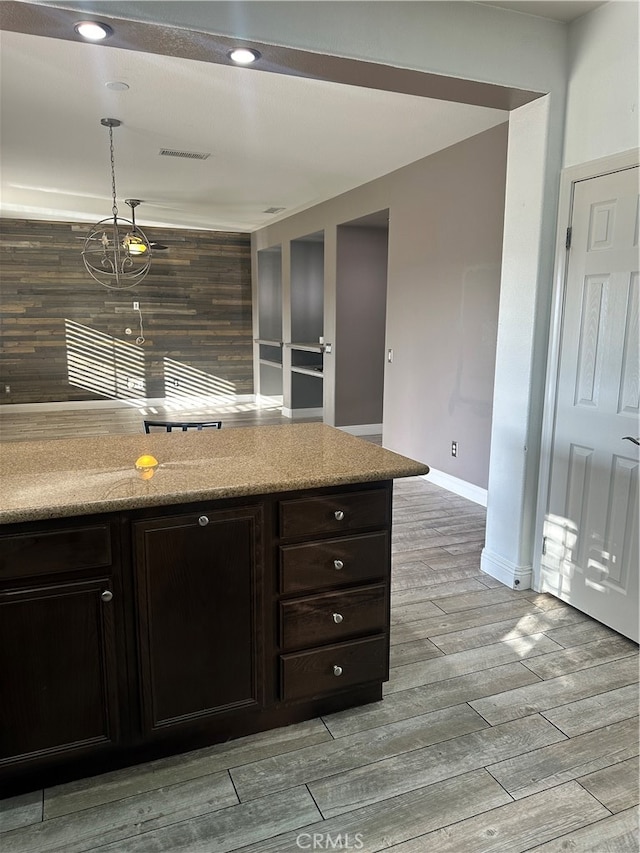 kitchen with light wood-type flooring, pendant lighting, and dark brown cabinets