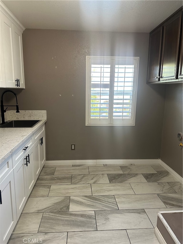 kitchen featuring sink, white cabinets, light stone countertops, and light tile patterned floors