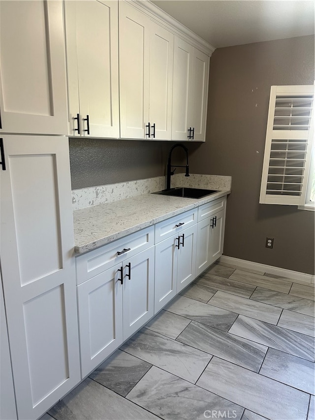 kitchen featuring sink, white cabinetry, light stone counters, and light tile patterned floors