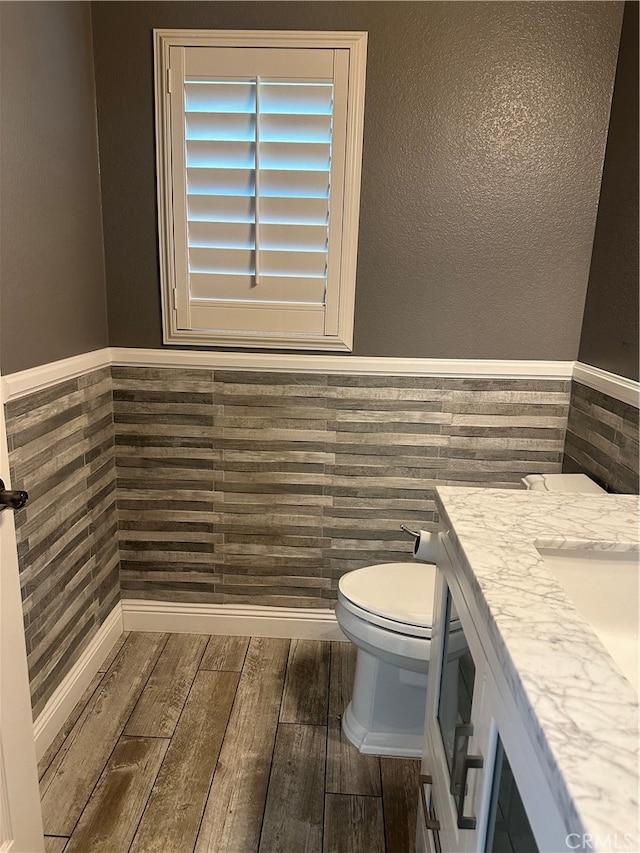 bathroom with tile walls, toilet, and vanity