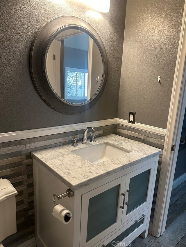 bathroom with tile walls, toilet, and vanity