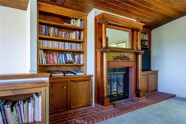 interior space featuring dark colored carpet, wooden ceiling, and a fireplace