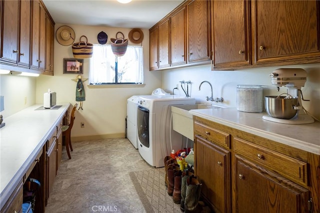 clothes washing area with washer and clothes dryer, cabinets, and sink