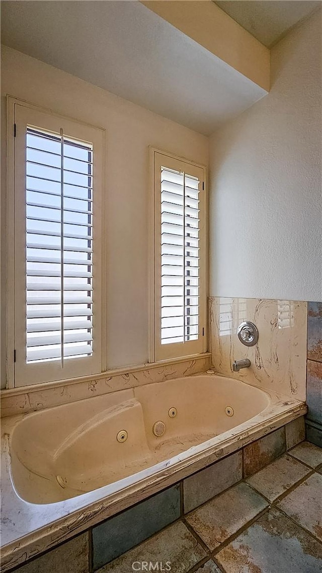 bathroom with a tub to relax in and a healthy amount of sunlight