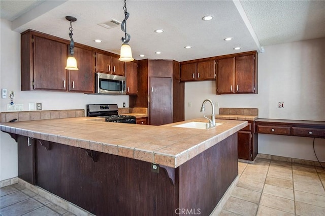 kitchen featuring a kitchen bar, kitchen peninsula, stainless steel appliances, sink, and decorative light fixtures