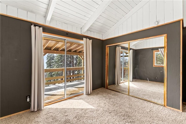 interior space with carpet floors, lofted ceiling with beams, a closet, and wood walls