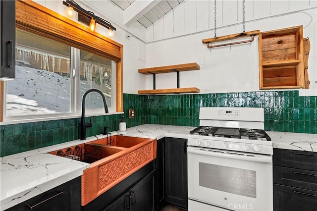 kitchen with lofted ceiling, sink, light stone countertops, and gas range gas stove