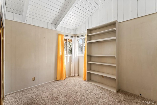 interior space featuring carpet floors, lofted ceiling with beams, and wood walls