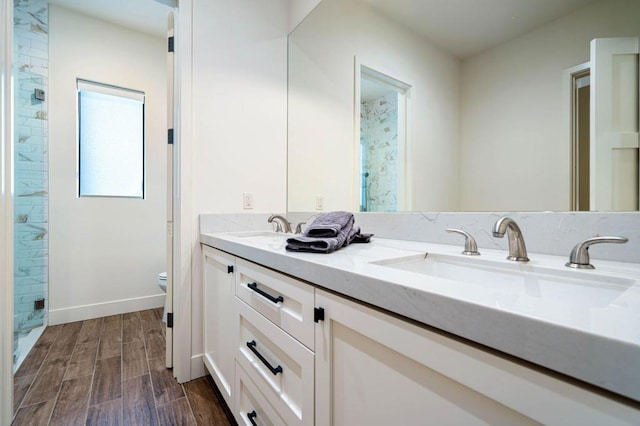 bathroom with wood-type flooring, oversized vanity, toilet, and double sink