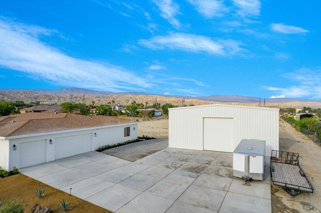 exterior space featuring a garage, a mountain view, and an outdoor structure