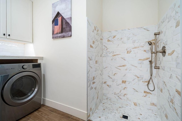 bathroom with a tile shower, washer / clothes dryer, and wood-type flooring