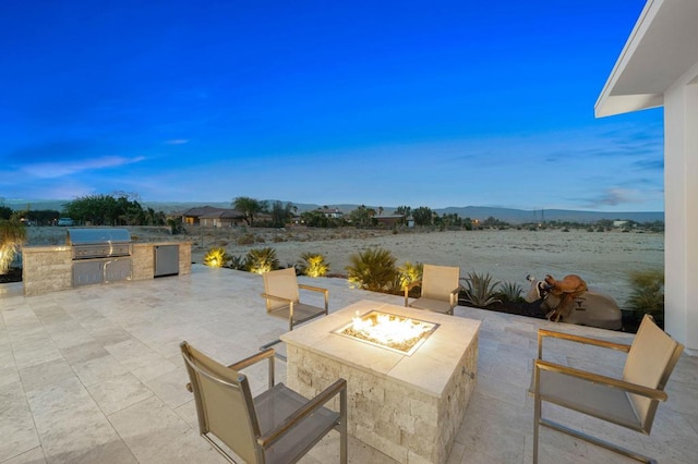 view of terrace with a grill, exterior kitchen, and an outdoor fire pit