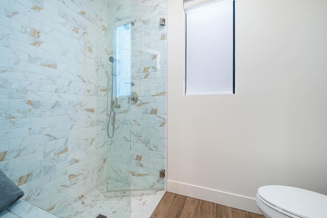 bathroom with tiled shower, hardwood / wood-style floors, and toilet