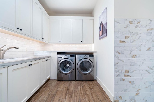 laundry room with hardwood / wood-style floors, cabinets, and washing machine and dryer