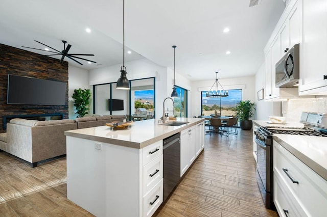 kitchen featuring light hardwood / wood-style floors, sink, white cabinets, a kitchen island with sink, and appliances with stainless steel finishes