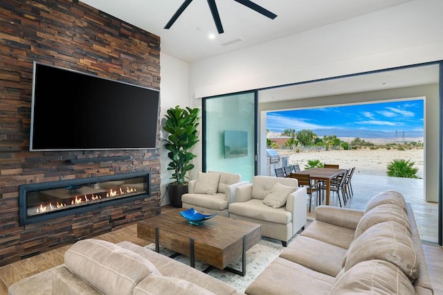 living room with hardwood / wood-style floors, ceiling fan, and a fireplace