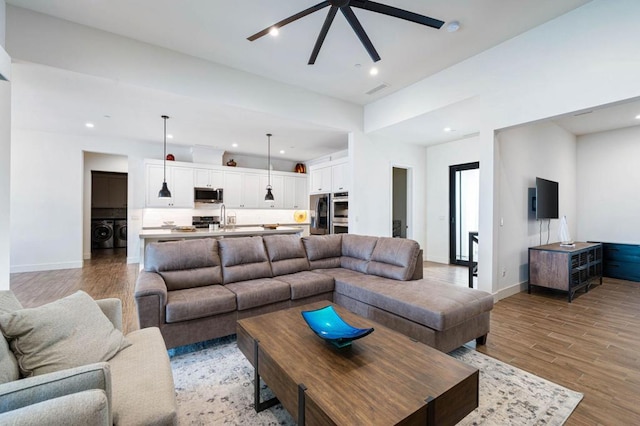 living room featuring sink, ceiling fan, light wood-type flooring, and washing machine and dryer